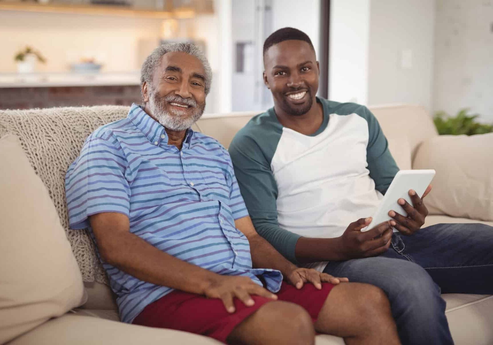 Two people smiling while holding a tablet.